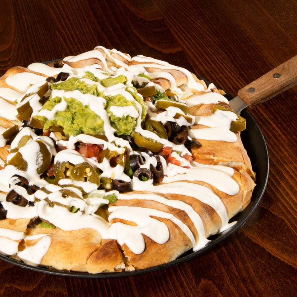 Gelsosomo's Pizzeria's taco pizza with guacamole, jalapeños, olives, and sour cream drizzle.